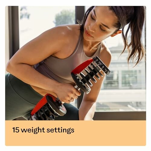 Woman using adjustable dumbbell with 15 weight settings.